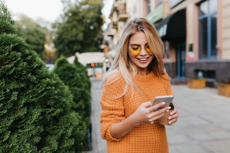 Uśmiechnięta blondynka przeglądająca telefon